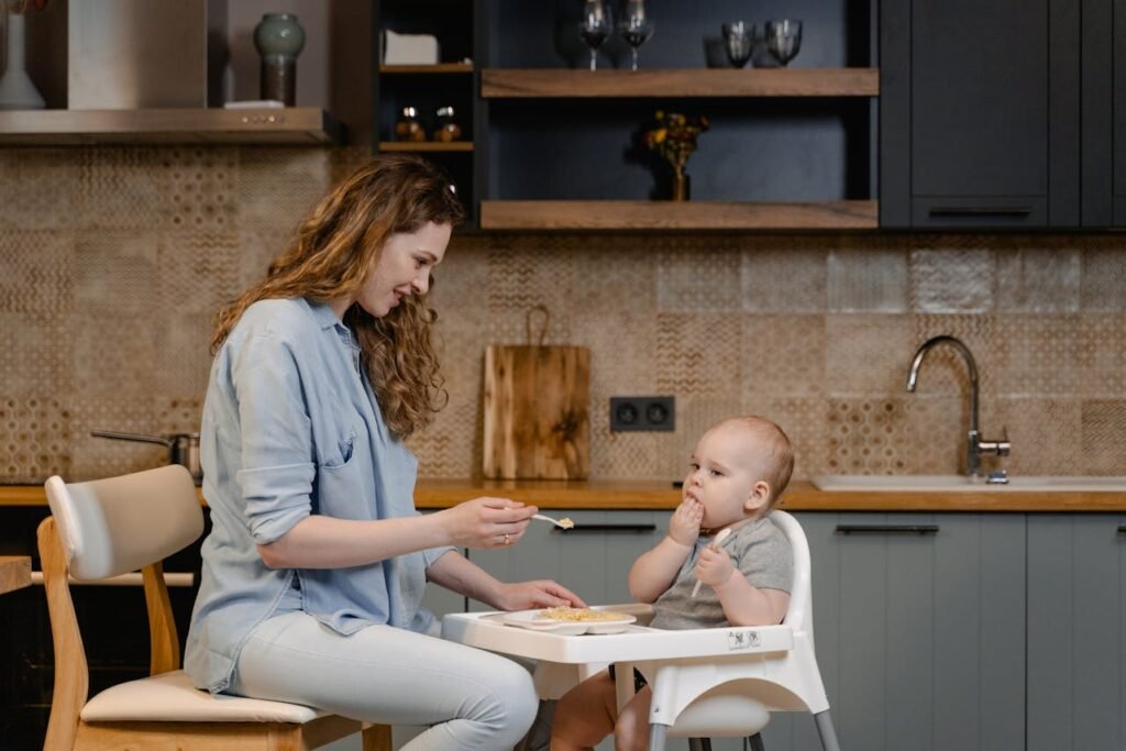 Mother feeding baby in high chair - heavy metals in baby food safety guide
